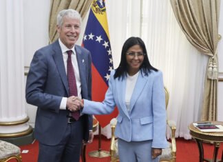 Secretario de Energía defiende acuerdo petróleo con Venezuela El presidente de EEUU Donald Trump de traje oscuro y corbata roja estrecha la mano de una la presidente de venezuela Delcy Rodriguez con gafas y blazer azul claro frente a la bandera de Venezuela, en un elegante salón durante un encuentro relacionado con el petróleo.